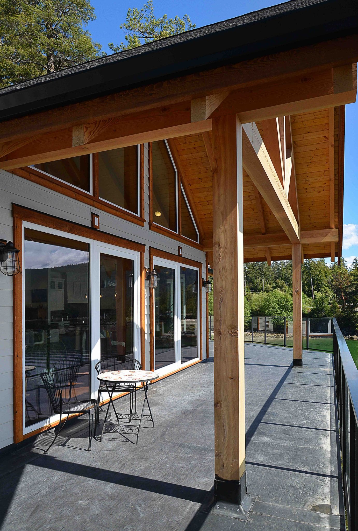 Pender Harbour Timber Frame Home | Streamline Design Ltd The deck and exposed beams outside a timber frame home
